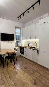 a kitchen with white cabinets and a wooden table at CityCenterApartments/M32/6 in Bielsko-Biała