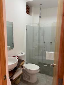 a bathroom with a toilet and a glass shower at Santa Cecilia Hotel in Oaxaca City