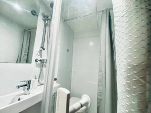 a white bathroom with a shower and a sink at Apt 08 Beachside Beauty Central Studio Steps from Cafes in Brighton & Hove +40 photos