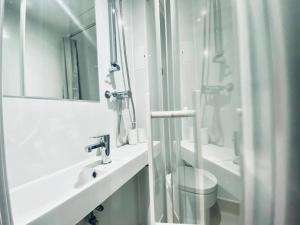 a white bathroom with a shower and a sink at Apt 08 Beachside Beauty Central Studio Steps from Cafes in Brighton & Hove
