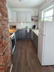 a kitchen with a white refrigerator and a brick wall at Fjellveien 4 in Vadsø