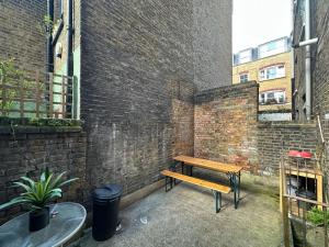 Whitechapel Station Rooms في لندن: مقعد خشبي بجانب جدار من الطوب