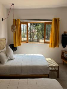 a bedroom with a bed and a window with yellow curtains at Santa Cecilia Hotel in Oaxaca City
