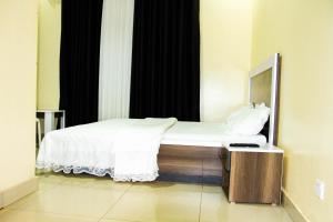 Schlafzimmer mit einem weißen Bett und einem Spiegel in der Unterkunft Branice Guest House in Kigali