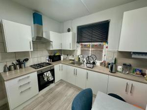 a kitchen with white cabinets and a stove top oven at Whitechapel Station Rooms in London