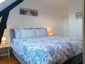 a bedroom with a bed with a blue and white comforter at Les gîtes de l'étang de la Forêt 2 in Brandivy