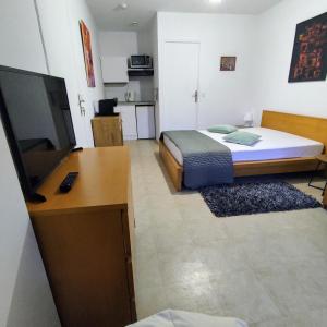 a bedroom with a bed and a desk with a television at Coeuilly village parisien Champigny sur Marne in Champigny-sur-Marne
