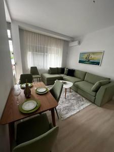 a living room with a table and a couch at Green Apartment Durrës in Durrës