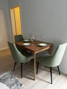 a wooden table with green chairs and a dining room at Green Apartment Durrës in Durrës