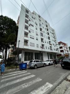 a large white building with cars parked in front of it at Green Apartment Durrës in Durrës