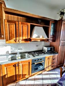 uma cozinha com armários de madeira e um lavatório em -La Terrazza nel Vigneto- [Golfo dei Poeti] em Tellaro