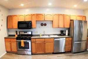 una cocina con armarios de madera y electrodomésticos de acero inoxidable en 2 Bedroom East Carson Street Sanctuary en Pittsburgh