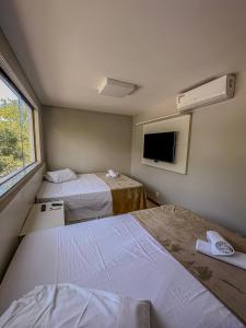a hotel room with two beds and a tv at Solaris Forever in Imbassai