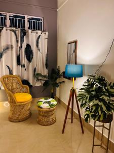 a room with two chairs and a lamp and a plant at Ujoni Homestay in Duliajan in Duliāgaon