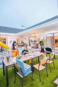 a group of people sitting around a table in a yard at Anya Pool Villa Pattaya in Ban Huai Yai