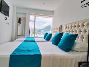 a bedroom with a large bed with blue pillows at Hotel Batan-127 in Bogotá