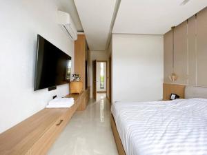 a bedroom with a bed and a flat screen tv at Anya Pool Villa Pattaya in Ban Huai Yai