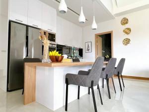 a kitchen with a bar with chairs and a counter at Anya Pool Villa Pattaya in Ban Huai Yai