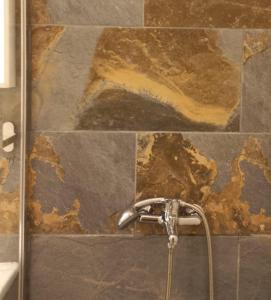 a bathroom with a shower faucet and a stone wall at Casa con jardín y barbacoa cerca del mar in Puerto del Rosario