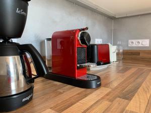 - Cafetera roja en la parte superior de un suelo de madera en Magnifique appartement 8 couchages dans villa historique, en Jausiers