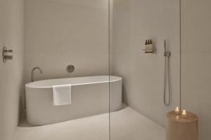 a white bathroom with a tub and a glass shower at The Riviera Maya EDITION at Kanai in Playa del Carmen