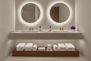 a bathroom with two mirrors and a sink with towels at The Riviera Maya EDITION at Kanai in Playa del Carmen