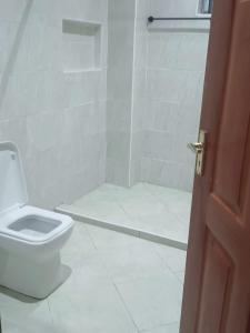 biała łazienka z toaletą i prysznicem w obiekcie Lagos Diani w mieście Diani Beach