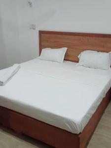 a bed with white sheets and pillows on it at Lagos Diani in Diani Beach