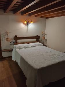 a bed in a bedroom with two lights on the wall at Pension Castio in Santillana del Mar