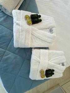 two white towels with buttons on a bed at The 3 Little Pigs apartments in Sidari