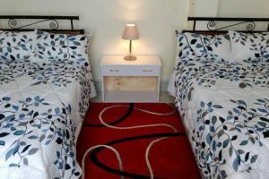 een slaapkamer met 2 bedden en een rood tapijt bij Fully furnished 3br, master ensuite penthouse. in Ruaka