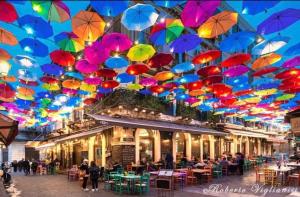 a bunch of colorful umbrellas hanging from a building at La Via Di Mezzo in Catania