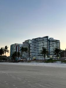 a large building with palm trees in front of a beach at Apartamento na praia de Ilhéus in Ilhéus