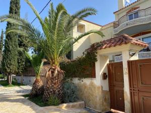 two palm trees in front of a house at Pool Garden House near the Sea in Vari