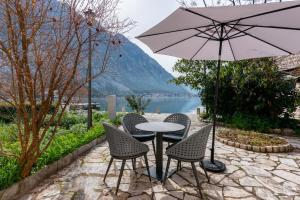 un tavolo con sedie e un ombrellone su un patio di Casa Spada by Belsize a Kotor (Cattaro)