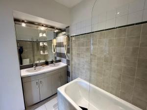 La salle de bains est pourvue de 2 lavabos, d'une baignoire et d'un miroir. dans l'établissement Le Richelieu Bacchus, à Fontainebleau