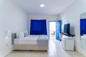 a bedroom with a bed and a tv and blue curtains at La Suite Praia Hotel in Caucaia