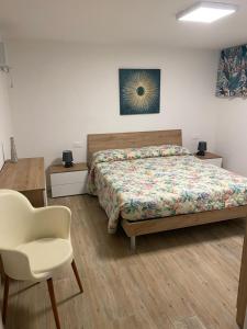 a bedroom with a bed and a white chair at Casa Sofia - Appartamento ristrutturato a Castiglione della Pescaia, località Rocchette in Castiglione della Pescaia