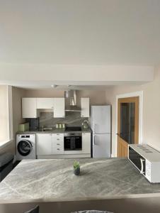 a white kitchen with a refrigerator and a microwave at Central 2 bedroom apartment in Wick