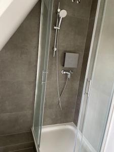 La salle de bains est pourvue d'une douche avec une porte en verre. dans l'établissement Kleine gemütliche Haushälfte, à Keitum