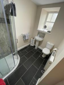 a bathroom with a shower and a toilet and a sink at Central 2 bedroom apartment in Wick
