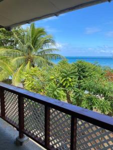 a balcony with a view of the ocean and palm trees at Bienvenue chez Fare Na’i in Fare