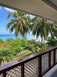 a balcony with a view of the ocean and palm trees at Bienvenue chez Fare Na’i in Fare