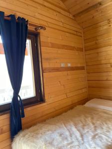 a bedroom in a log cabin with a window at Thethi Paradise Hotel & Restaurant in Theth