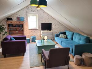 a living room with blue couches and a tv at bloom-inn gastvrij genieten in Doornenburg