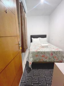 a small bedroom with a bed and a door at Blue Hale in Guarujá