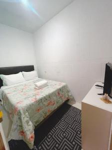 um pequeno quarto com uma cama e uma secretária em Blue Hale no Guarujá