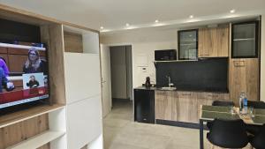 a living room with a flat screen tv and a kitchen at Apartamentos O Caneiro in Portomarin