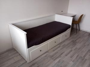 ein weißes Bett mit einer schwarzen Matratze und einem Schreibtisch in der Unterkunft Vaidaugu Cosy Apartment, Klaipeda in Klaipėda