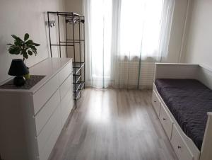 ein Schlafzimmer mit einem Bett und eine Kommode mit einer Pflanze in der Unterkunft Vaidaugu Cosy Apartment, Klaipeda in Klaipėda
